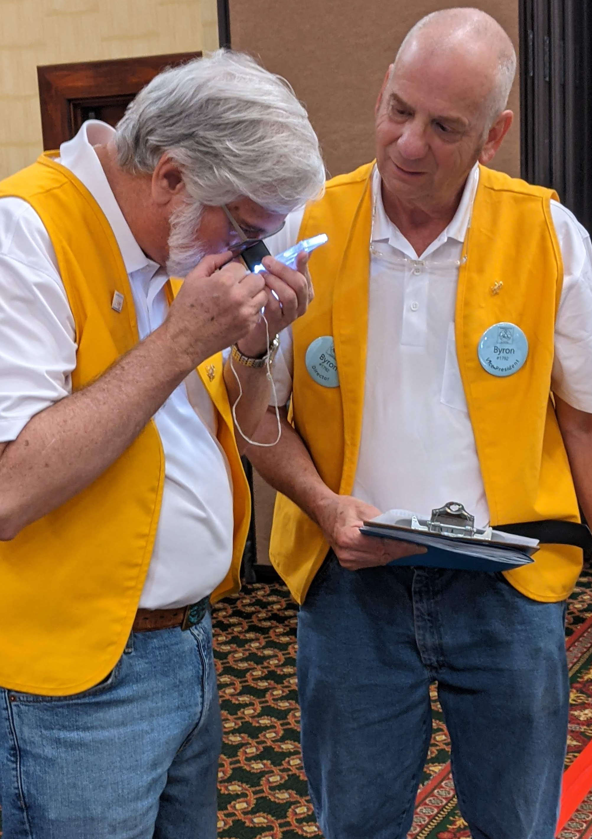 Byron Kesner and Bill DeWeese in their club vests examine a coin