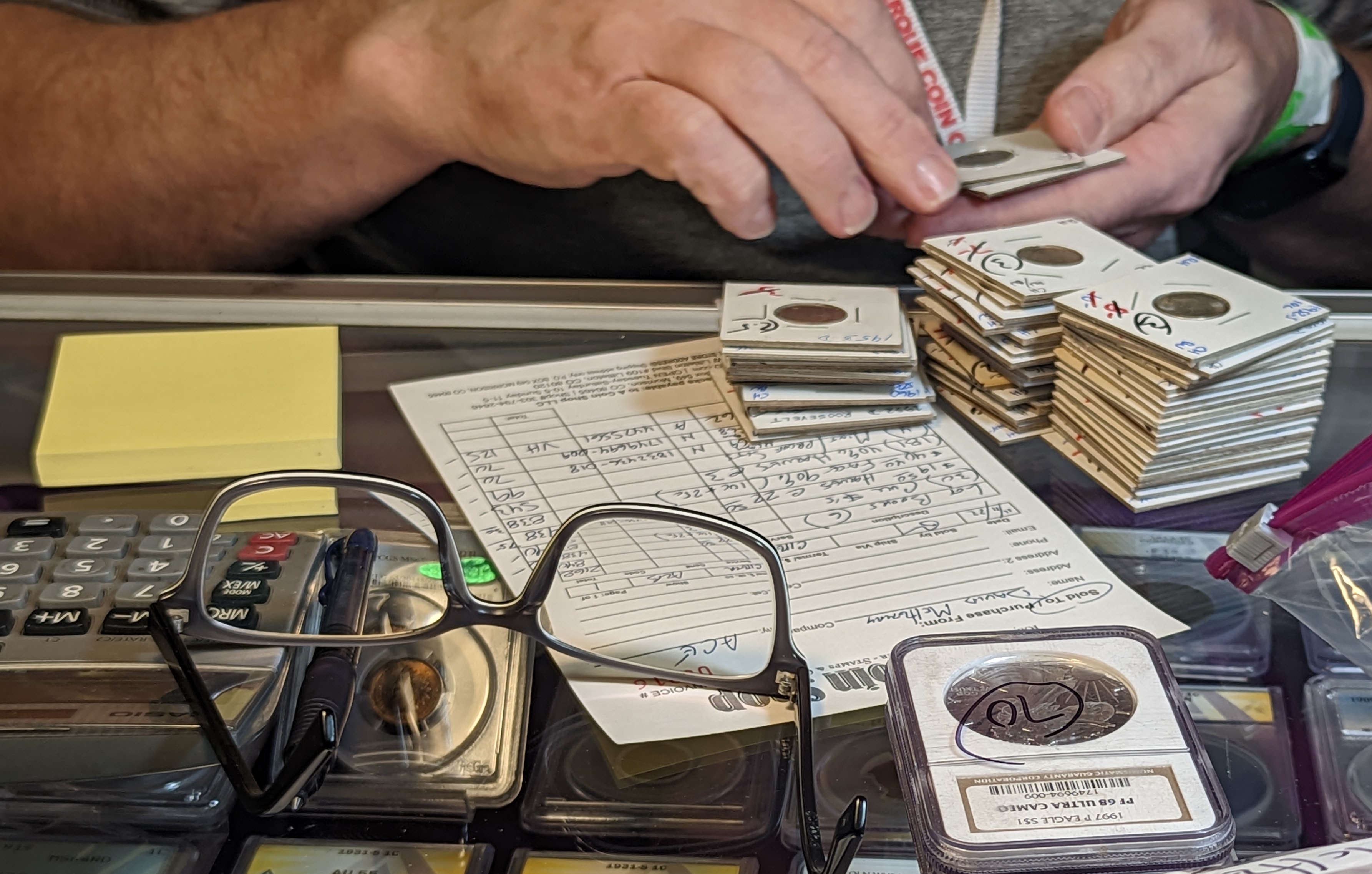A dealer takes inventory of his wares; closeup of his hands and table